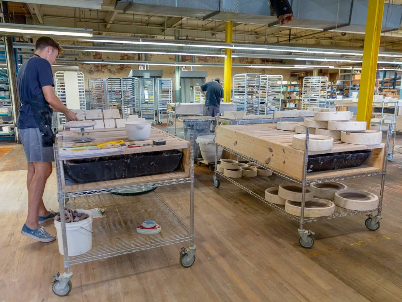 Several employees, workstations and products scattered across the production area of the studio.