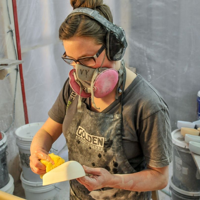 A caster wearing protective gear sponges off a piece